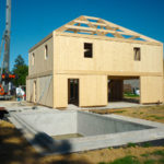 Construction en CLT d’une maison familiale : montage des murs en panneaux bois lamellé-croisé pour une structure durable et performante.