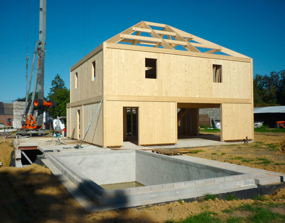 Construction en CLT d’une maison familiale : montage des murs en panneaux bois lamellé-croisé pour une structure durable et performante.
