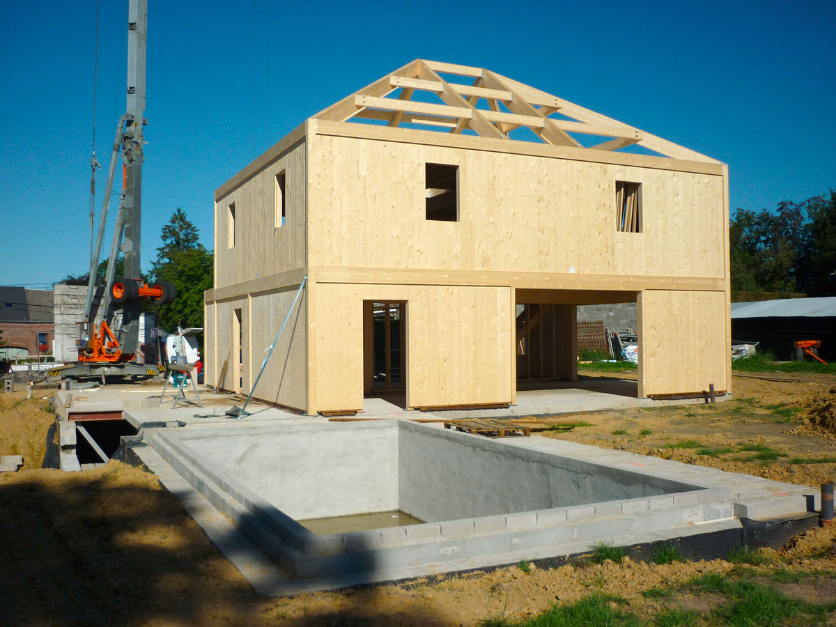Construction en CLT d’une maison familiale : montage des murs en panneaux bois lamellé-croisé pour une structure durable et performante.